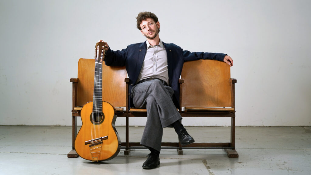 Giacomo Copiello seated beside his eight-string Brahms Guitar.